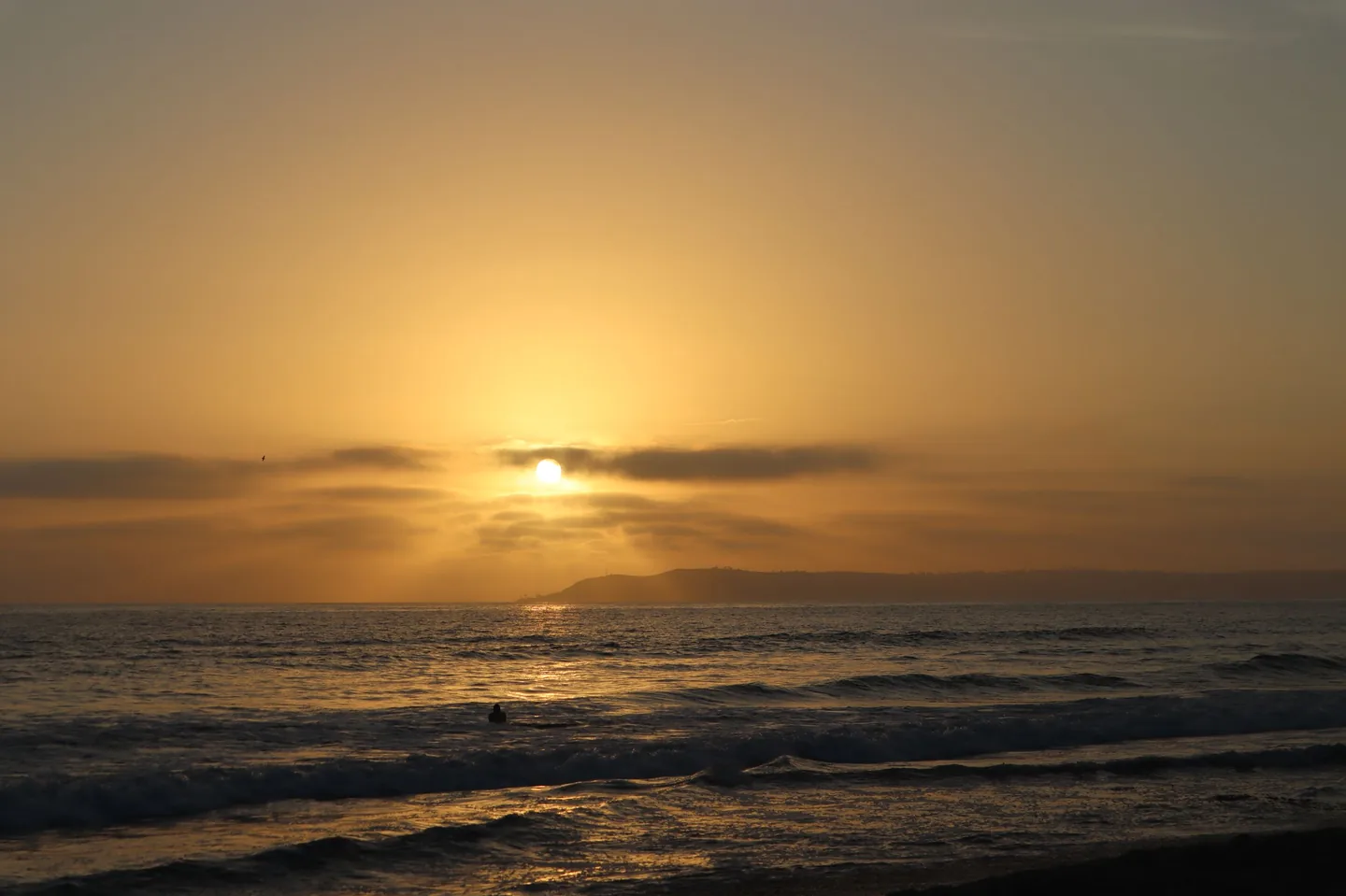 The sun setting over the ocean, waves rolling in