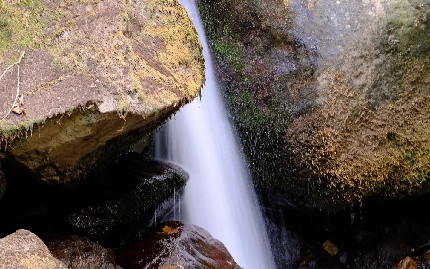 A waterfall falling between mossy rocks