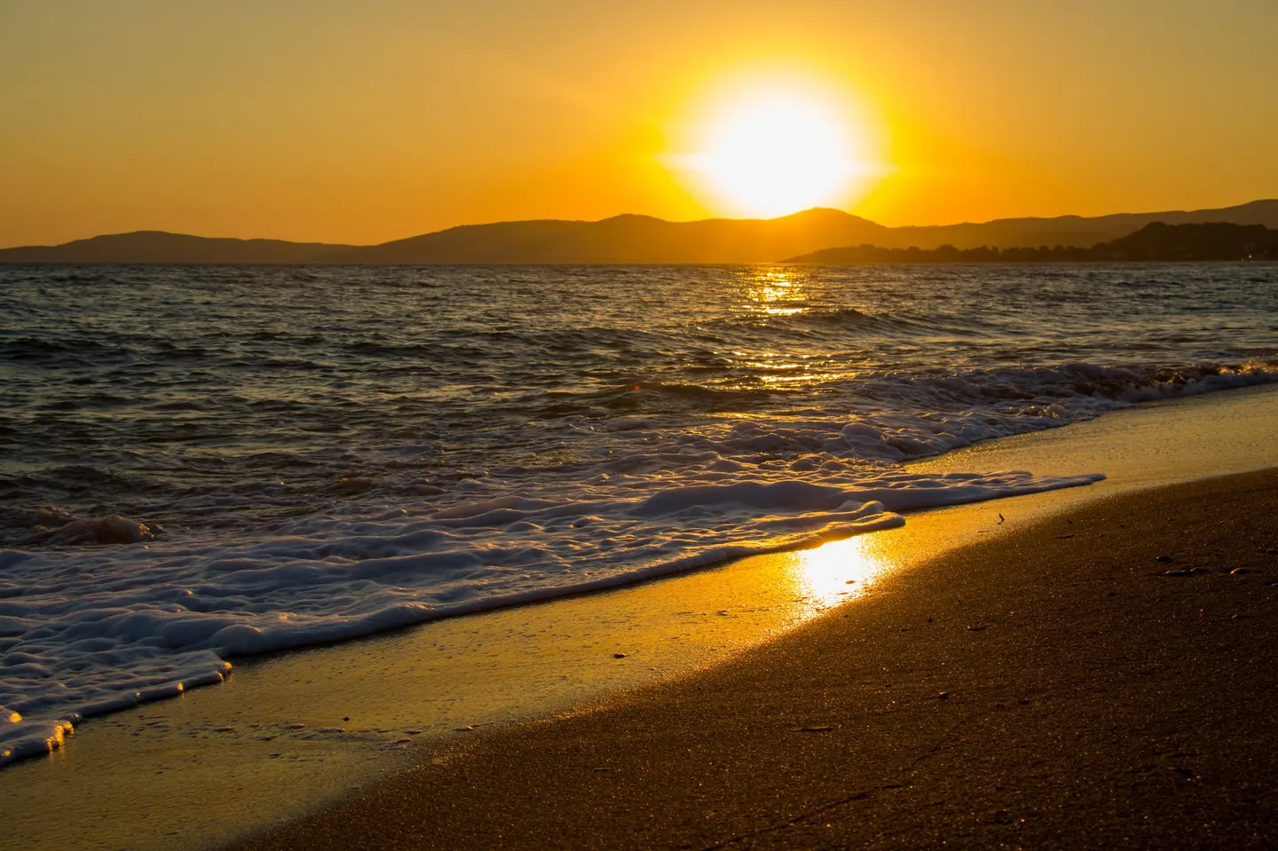 Waves rolling onto a sandy beach at golden hour